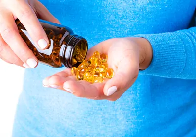 Closeup of a person pouring several dietary supplement capsules into their open palm.